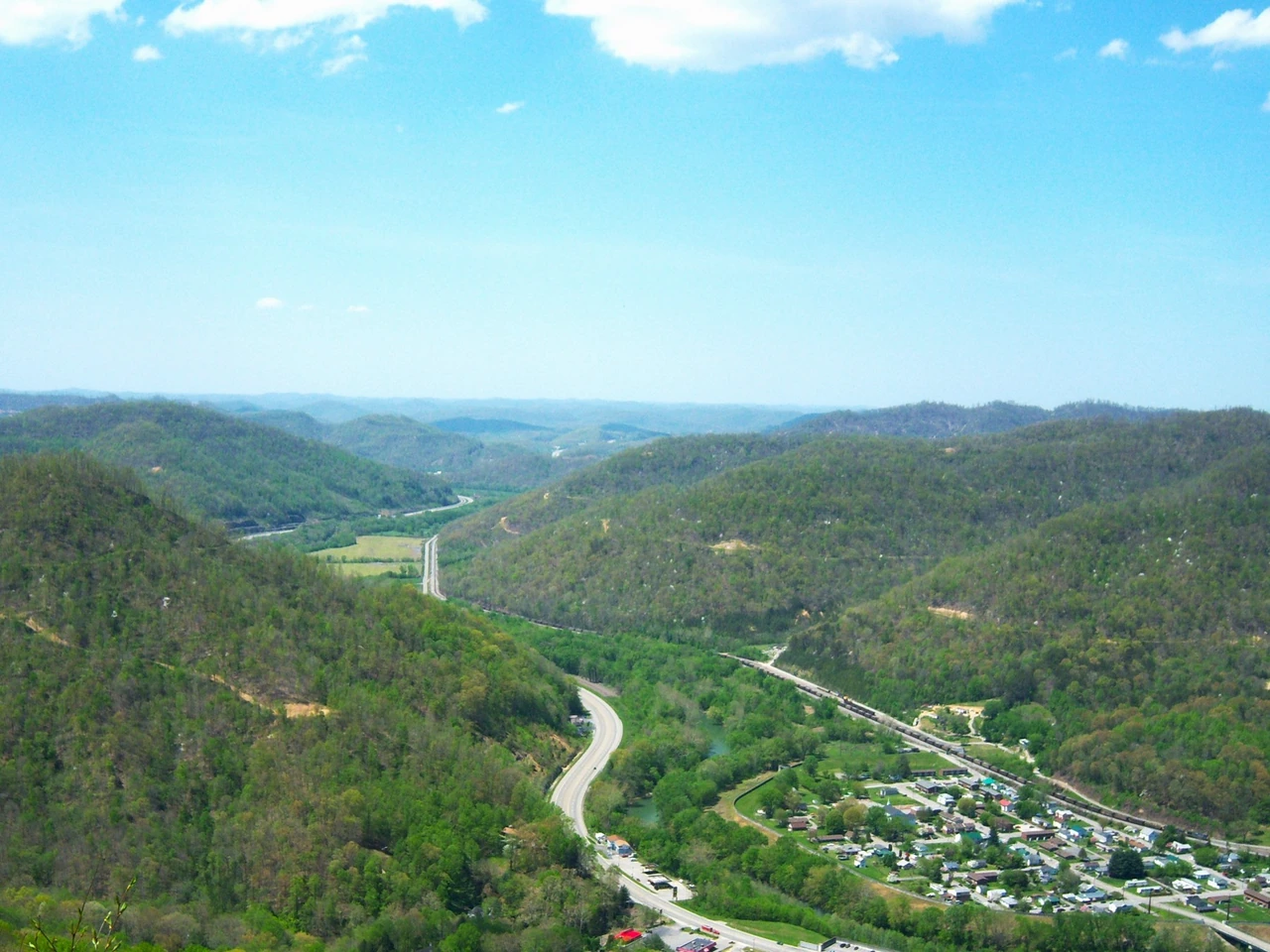 Pine Mountain overlook with wooded Kentucky ridges, roads and a settlement below.